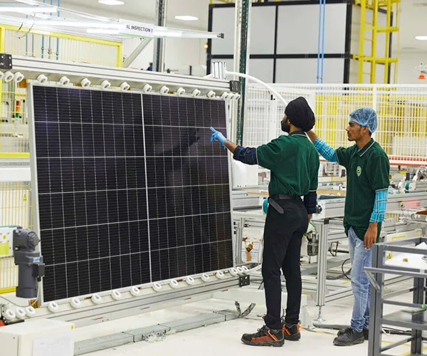ReNew technicians inspecting a solar module on the manufacturing line