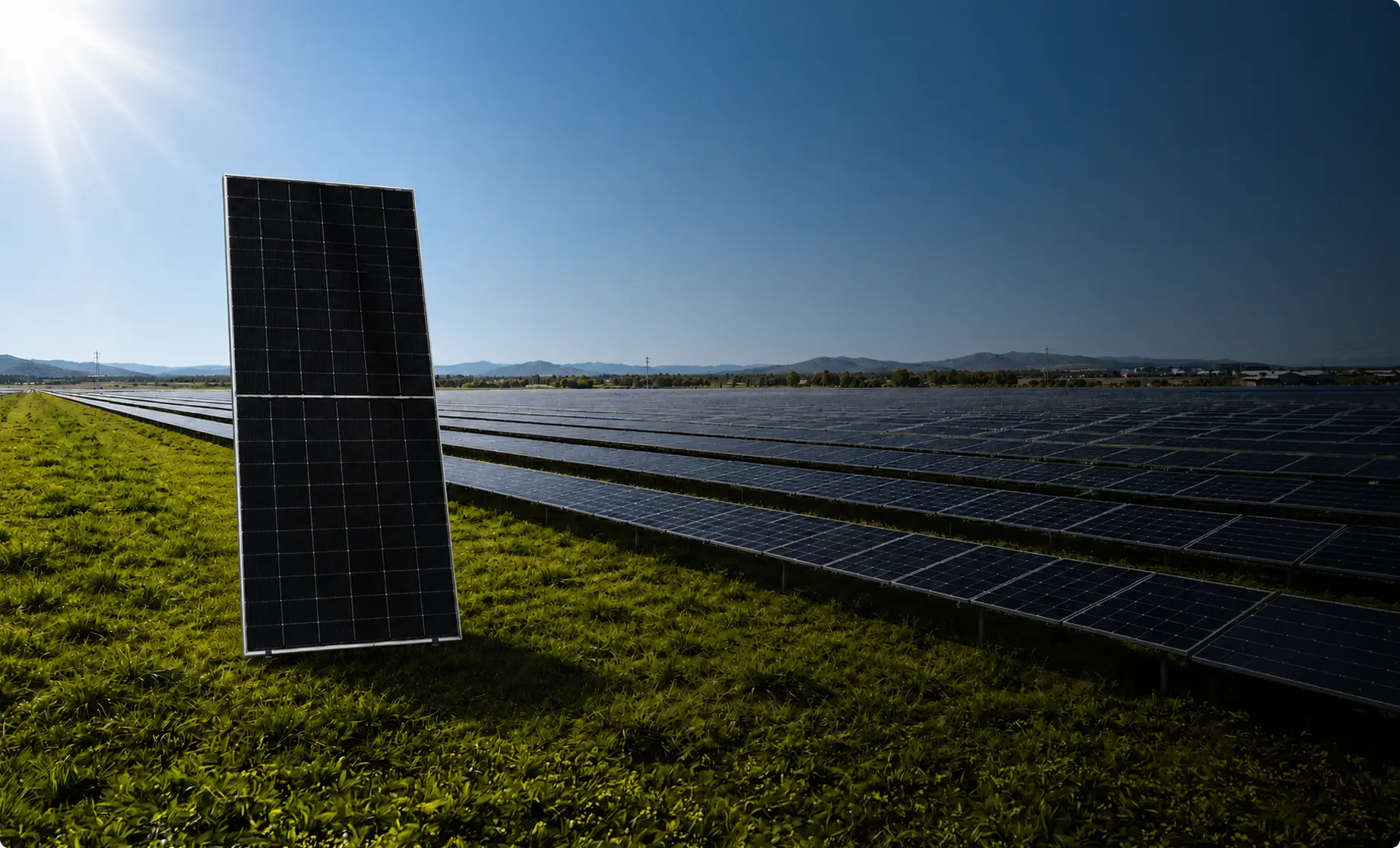 Two ReNew solar modules standing in a grassy valley at sunrise